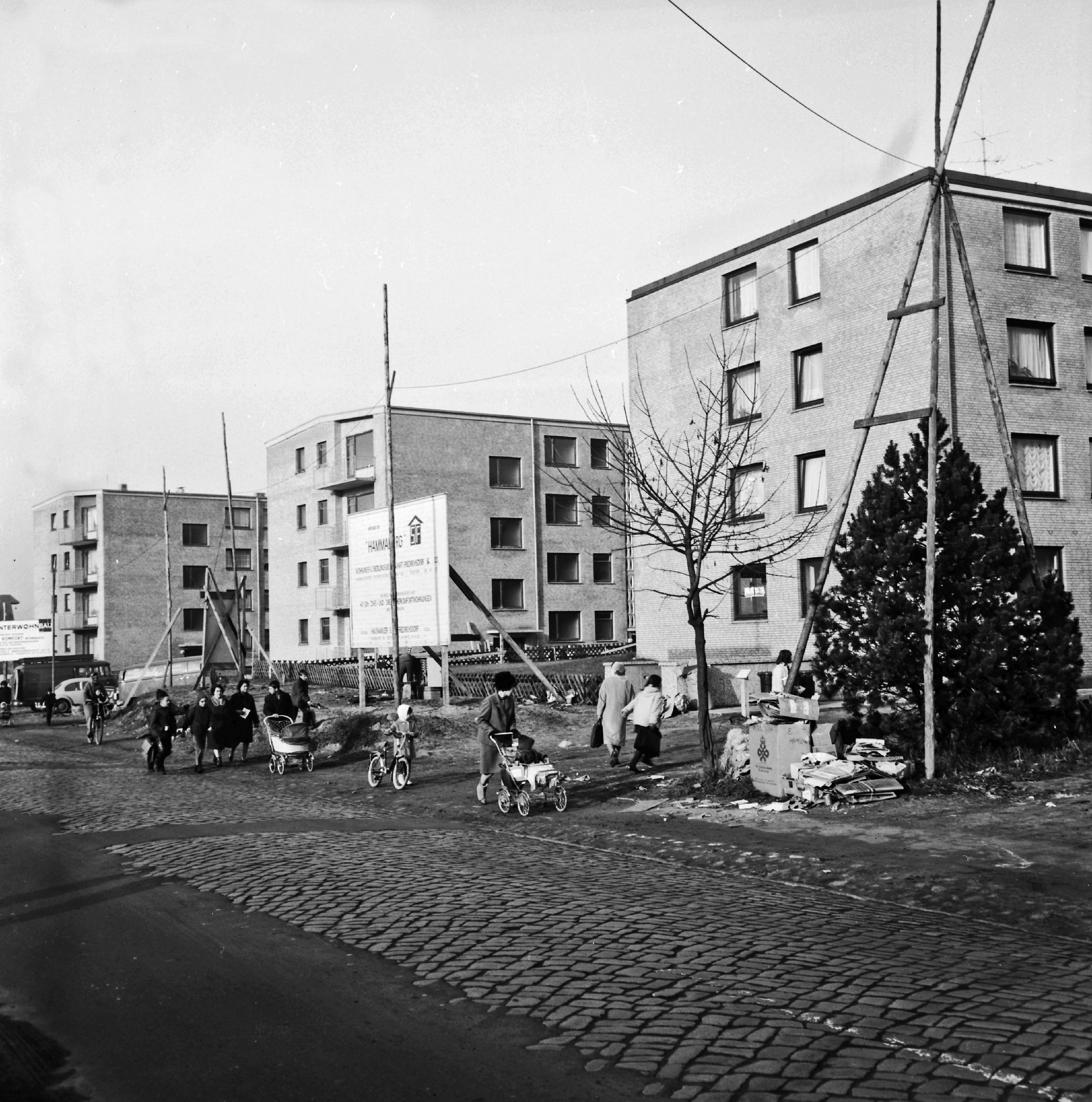 Barsbüttel: Wohnungsbau: Hauptstraße mit Kopfsteinpflaster: dahinter drei Wohnblocks des Bauprojekts 