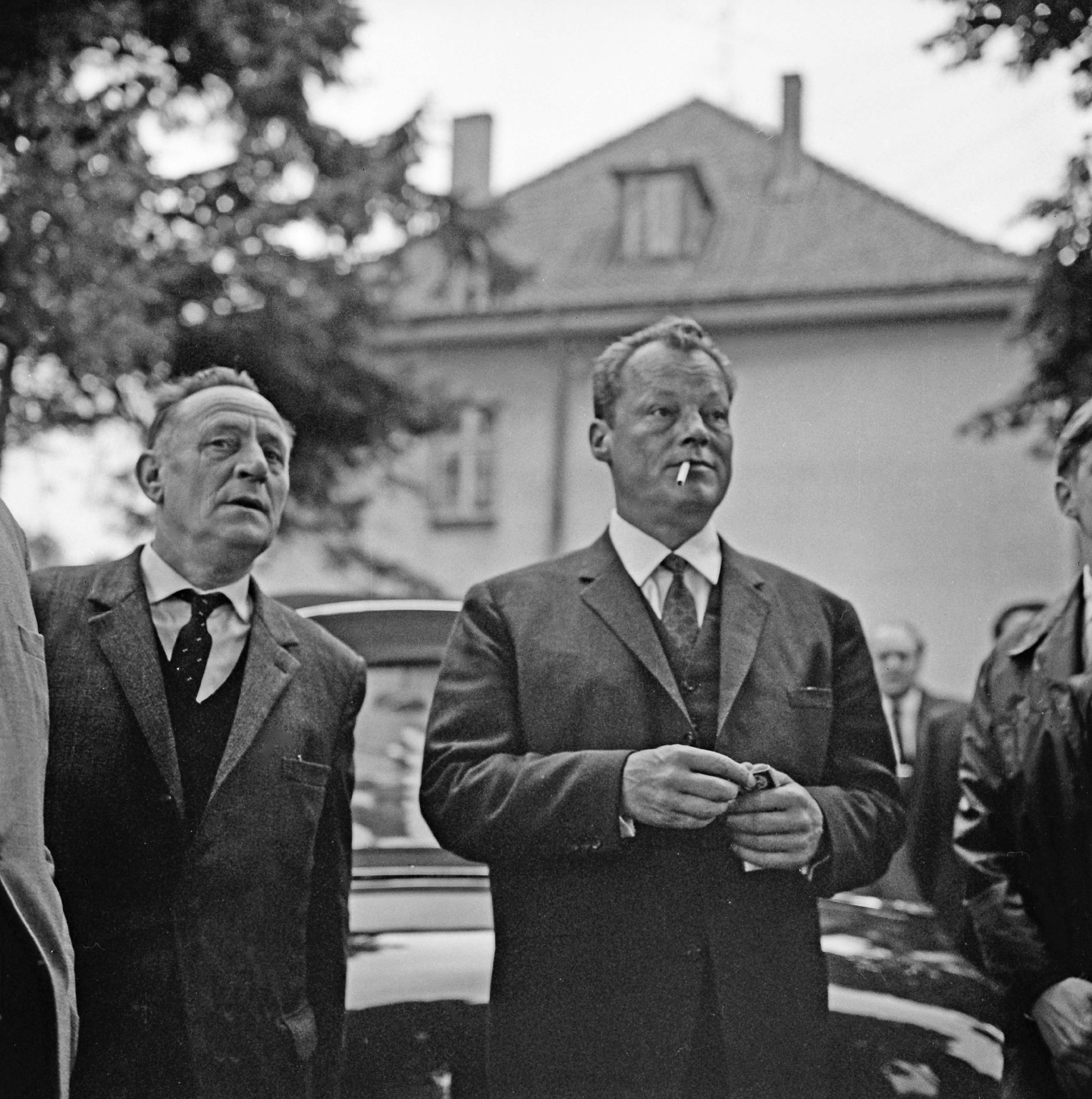 Bad Oldesloe: SPD: Bürgerpark: Naturtheater: Kundgebung zur Bundestagswahl am 19. September 1965: Ankunft des Kanzlerkandidaten Willy Brandt, SPD-Parteivorsitzender und Regierender Bürgermeister von Berlin, mit dem Landtagsabgeordneten Otto Gramcko: dahinter Pkw: hinten Gebäude und Ehrengäste: 18. September 1965  vorn v.l.n.r.: Otto Gramcko, Willy Brandt