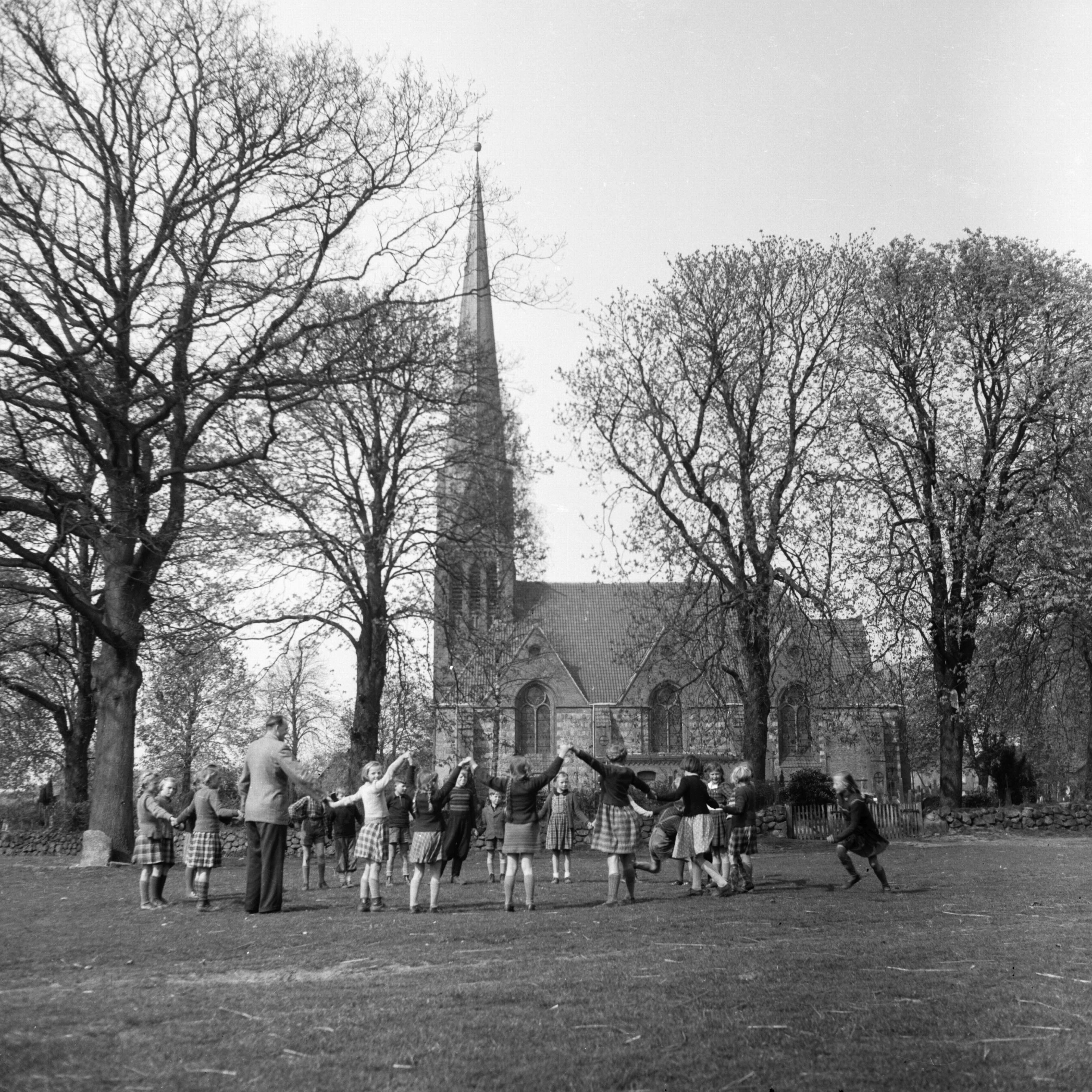 Siek: Friedenskirche Siek: Außenansicht von Süden: vorn Dorfanger: darauf Schulkinder mit Lehrer beim Spiel: dahinter Kirchhof mit Bäumen, ca. 1954