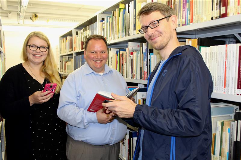 Sarah Walter (v.l.), Kreisarchivar Stefan Watzlawzik und Tim Schumann stellen die Titel der Präsenzbibliothek zu Stormarn ins Internet